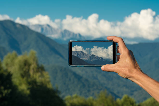 istock Hand making photo with smartphone camera closeup, view tourist hands using gadget phone in travel on background mountains and landscape 1014301176