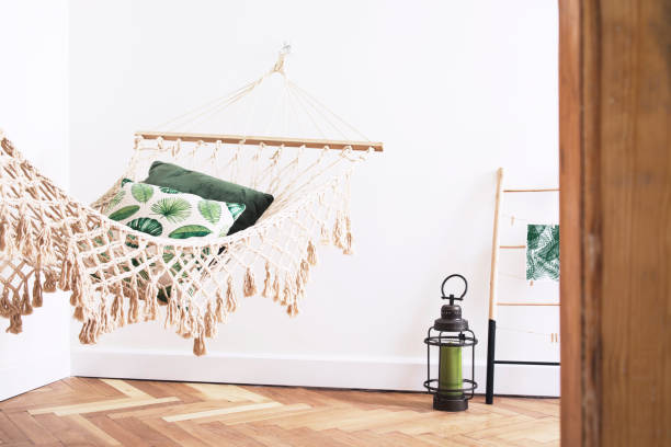 istock Modern and stylish bedroom with natural string hammock, plants and shelves with accessories. Bright and sunny bedroom with brown wooden parquet. 1014313146