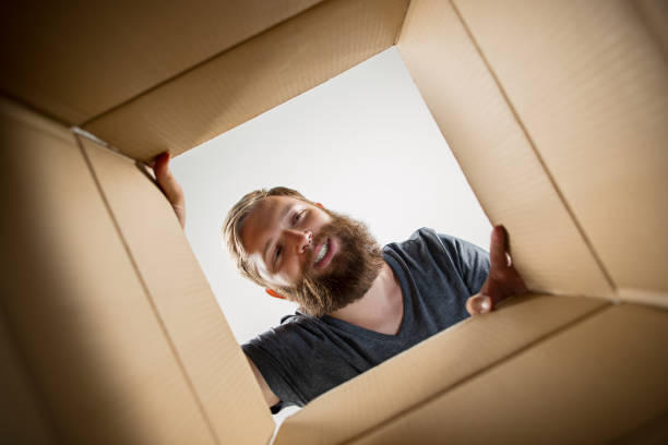 istock Man unpacking and opening carton box and looking inside 1014313964