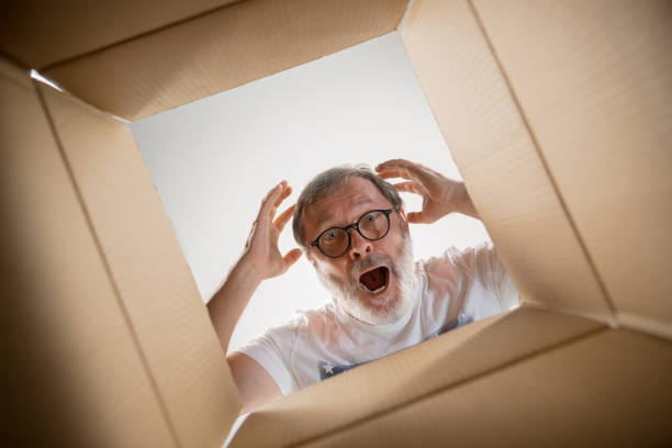 istock Man unpacking and opening carton box and looking inside 1014318004