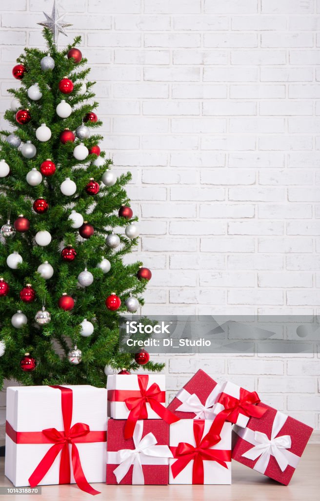 Foto de Caixas De Presente E Árvore De Natal Decorada Com Bolas Coloridas  Sobre Parede De Tijolo e mais fotos de stock de Bola - iStock