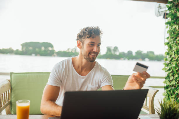 istock Joyful man with laptop looking at credit card 1014330126