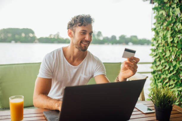 istock Joyful man typing on laptop and holding credit card 1014330130