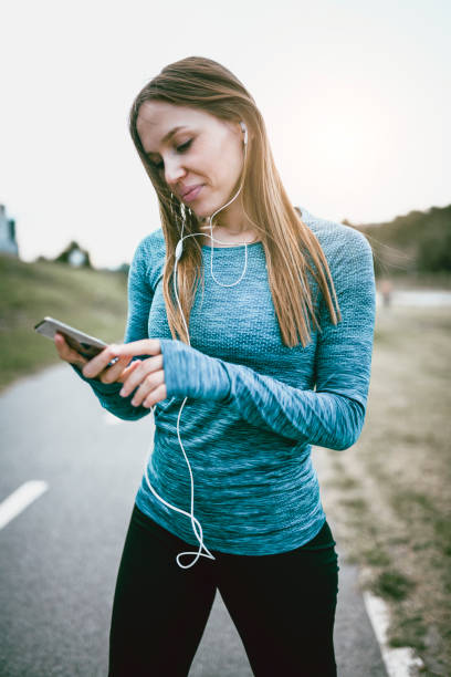 istock Female Athlete Setting Up A Playlist Before Jogging 1014333844