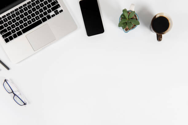istock Office table with laptop computer, smartphone, pen, notebook and coffee on isolated pure white background / Laptop and tablet mockup concept. (Selective Focus) 1014356980