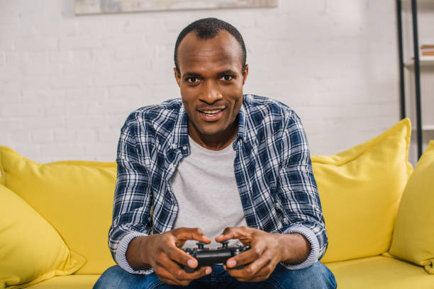 istock young african american man playing with joystick and smiling at camera 1014357952