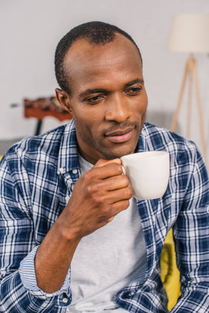 istock pensive young african american man holding coffee cup at home 1014358152