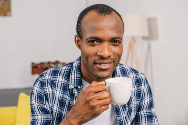 istock young african american man holding coffee cup and smiling at camera 1014358296