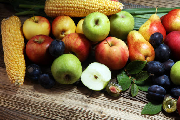 Various fresh fruits. Thanksgiving pumpkin, apples, and maize on rustic background