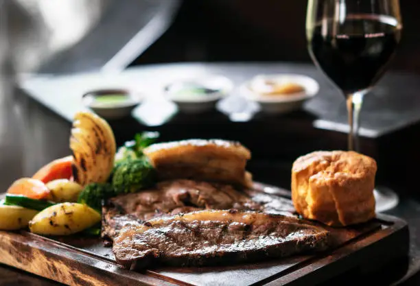 Photo of gourmet sunday roast beef traditional british meal set on old wooden pub table