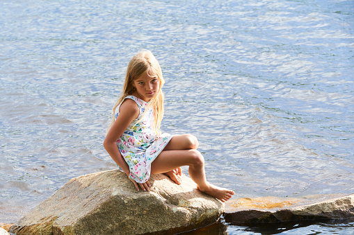 Child girl having fun on rock on the beach in summer