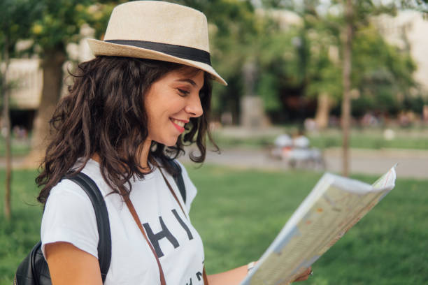 istock Young woman wearing summer hat looking at touristic map 1014415780