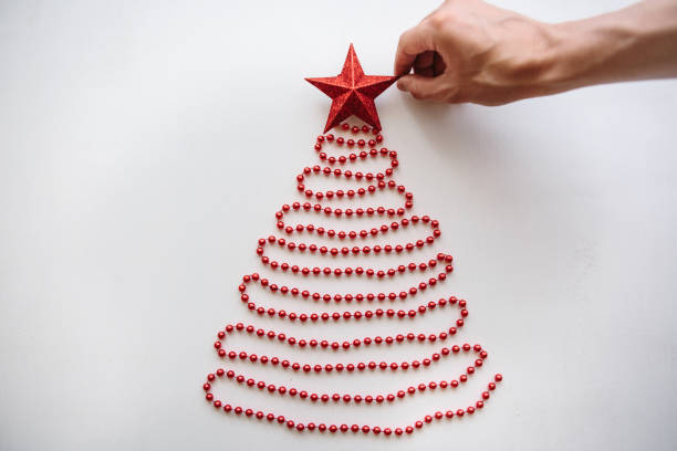 una persona hace un creativo árbol de navidad o año nuevo de granos en un estilo minimalistico y adorna con una estrella - mano sobre cadera fotografías e imágenes de stock