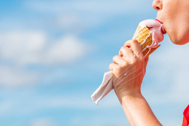istock Mouth eating Ice-cream Cone against blue sky. 1014421886