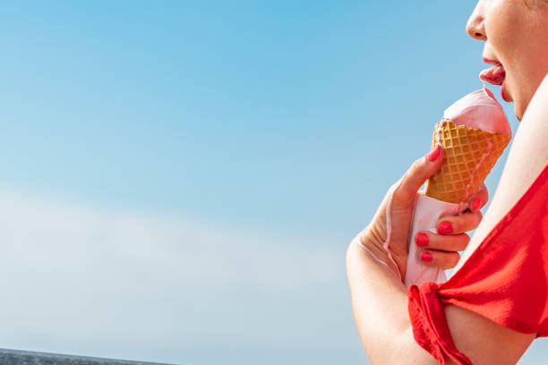 istock Mouth eating Ice-cream Cone against blue sky. 1014422020