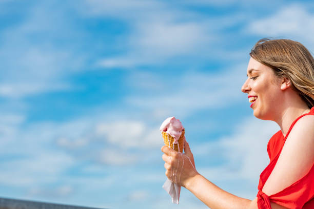 istock Mouth eating Ice-cream Cone against blue sky. 1014422056