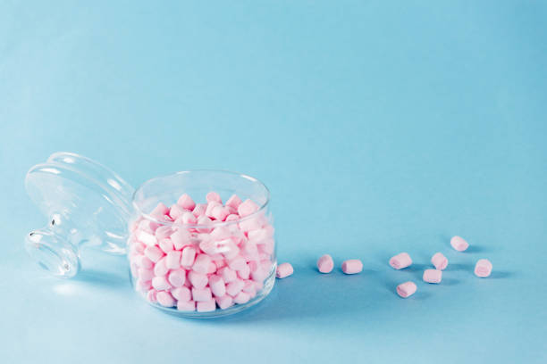 istock Creative minimal still life on pastel blue colored background. Glass bowl with cute pink marshmallows. Copyspace 1014426388