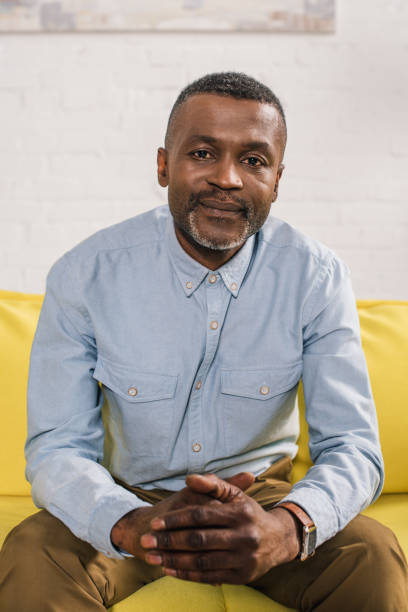 istock senior african american man sitting on couch and looking at camera 1014429792