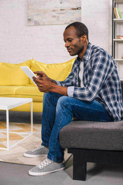 istock side view of smiling african american man using digital tablet at home 1014431954
