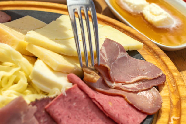 istock Fork in a cheese and salami, sliced ham, prosciutto platter. 1014432404