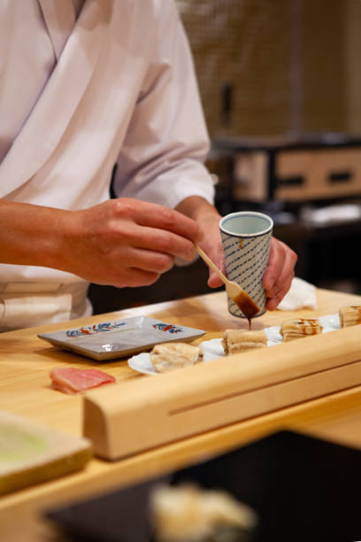 istock Professional and experienced sushi chef carefully add final touch with confident and dedication to his perfect sushi. 1014436590