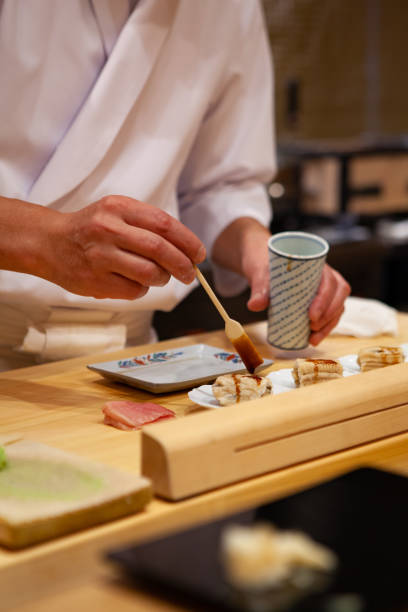 istock Professional and experienced sushi chef carefully add final touch with confident and dedication to his perfect sushi. 1014436608