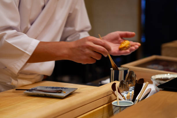 istock Professional and experienced sushi chef carefully add final touch with confident and dedication to his perfect sushi. 1014436640