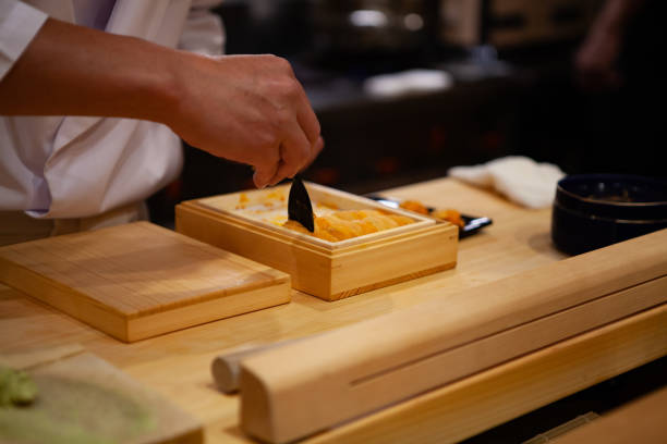istock Professional and experienced sushi chef is carefully spoon a delicate and top quality uni or sea urchin to make sushi. 1014436788