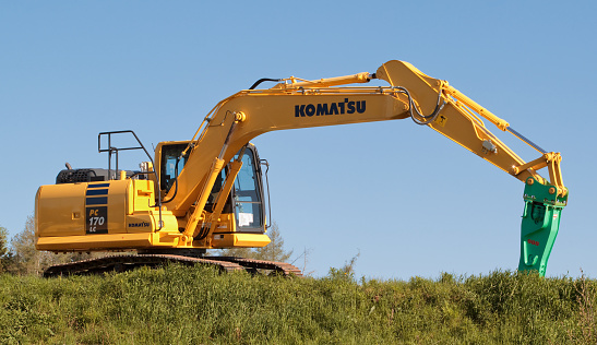 East Mountain, Canada - May 21, 2017: Komatsu excavator on grass with blue sky. Komatsu is a Japanese multinational corporation manufacturing heavy, industrial and military equipment.