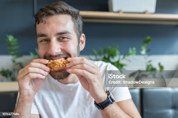 Giovane Adulto Che Mangia Ali Di Pollo Durante La Pausa Pranzo - Fotografie stock e altre immagini di Mangiare