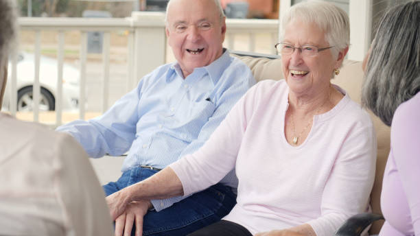 istock Senior couple hold hands as they visit with friends 1014480190