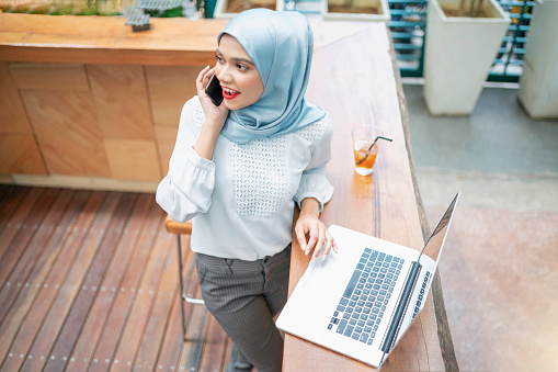 Beautiful malaysian businesswoman talking on the phone while at work.