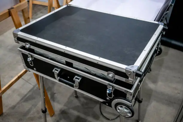 Photo of Black road case or flight case with wheels on metal stand for display in store
