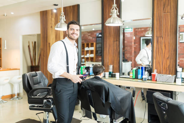 istock Barber Smiling While Hair Styling Customer In Shop 1014504282