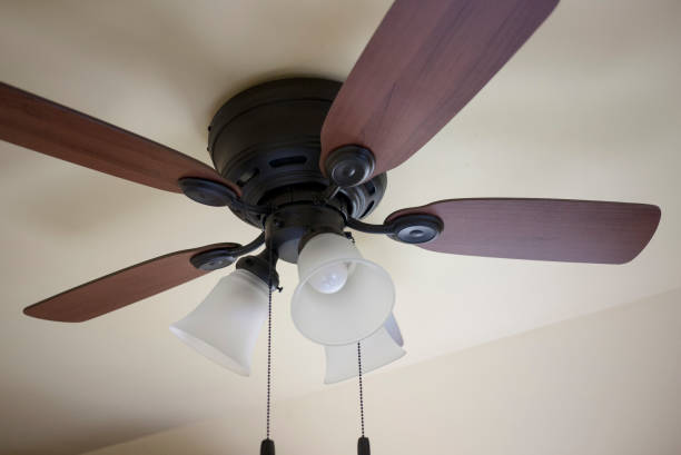Old Ceiling Fan Close-up of an old ceiling fan and light fixture in a cottage in Ontario. Wooden fan blades with a black metal body and chain switches. old fashioned ceiling fans stock pictures, royalty-free photos & images