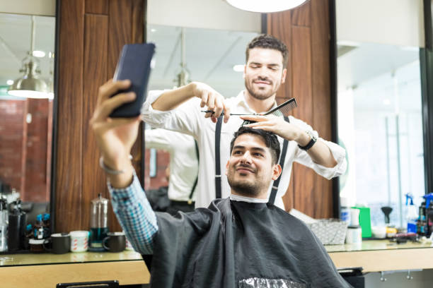 istock Customer Taking Selfie On Phone While Barber Styling His Hair 1014506644