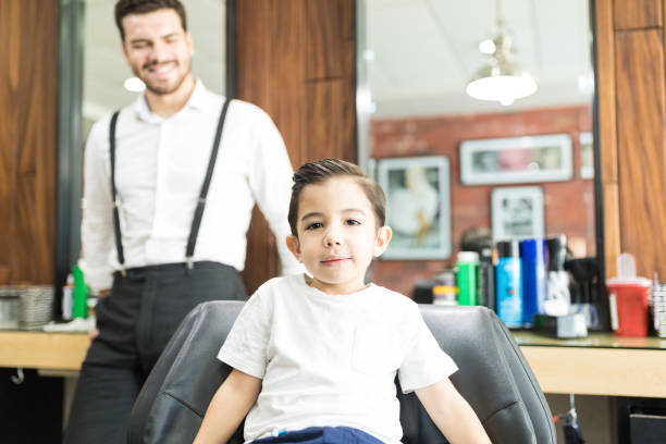 istock Stylish Boy Sitting On Chair While Barber Standing In Shop 1014513438