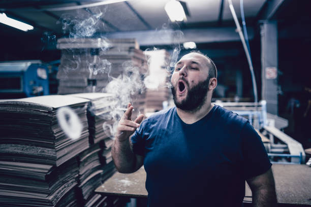 Male Factory Worker Smoking Inside Where It Is Not Allowed