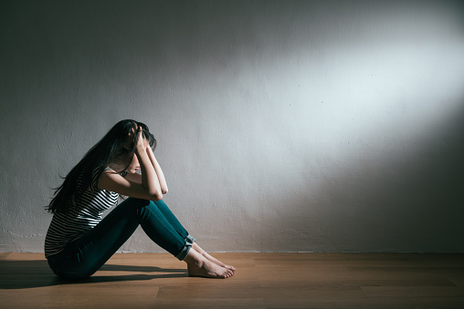 unhappy beauty girl having bad trouble and getting depression illness sitting on wooden floor daydreaming in white background.