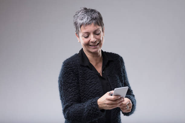 istock Attractive senior woman typing on her mobile 1014532420