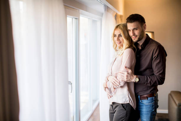 istock Young couple standing by the window in the room 1014532502