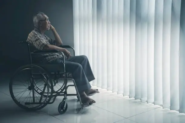 Picture of lonely elderly man looks pensive in the retirement home while sitting in the wheelchair