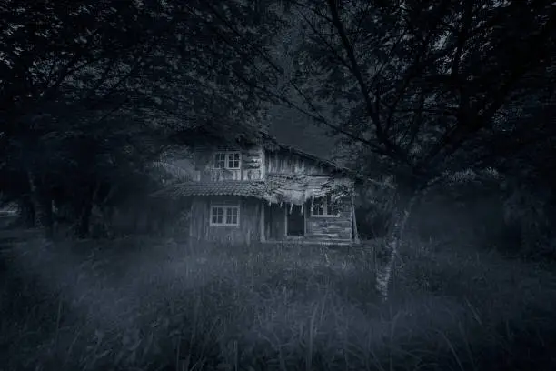 Image of spooky wooden house with damaged rooftop at night time