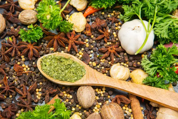 High angle view of variety herbs and spices with dried parsley in the wooden spoon