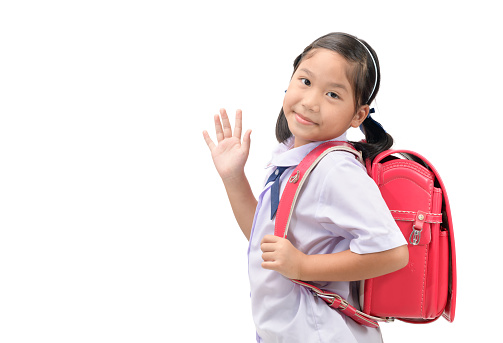 Asian girl student going to school and waving goodbye isolated on white background, back to school concept