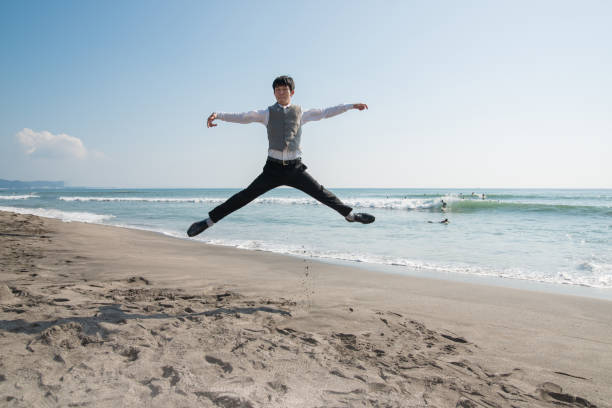 jumping businessman at beach - men businessman jumping levitation imagens e fotografias de stock