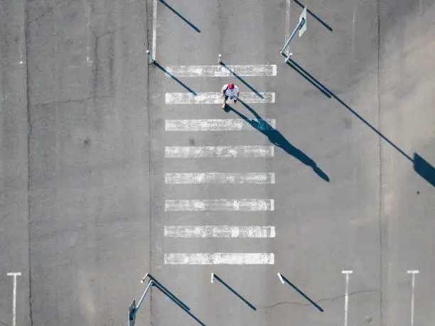 Photo of top aerial view of on man walking on the crosswalk in the street, abstract isolated disign with copy space
