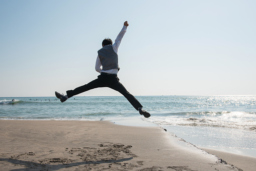 Jumping businessman at beach