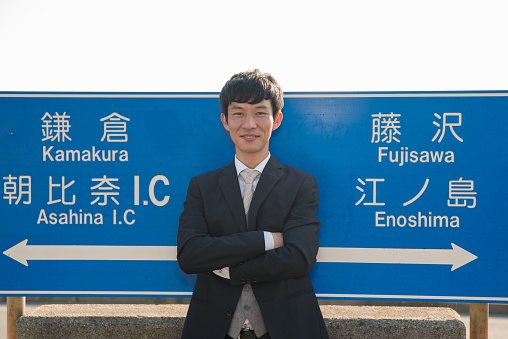 Businessman standing in front of traffic sign in Enoshima, Kanagawa, Japan