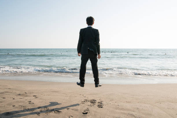 pływający biznesmen na plaży: ucieczka od codziennego życia - men businessman jumping levitation zdjęcia i obrazy z banku zdjęć